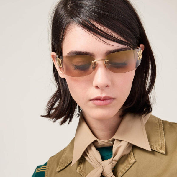 משקפי שמש מיו מיו בעיצוב מתכתי עם עדשות סגולות, מסגרת קלילה ולוגו אנכי מרשים.