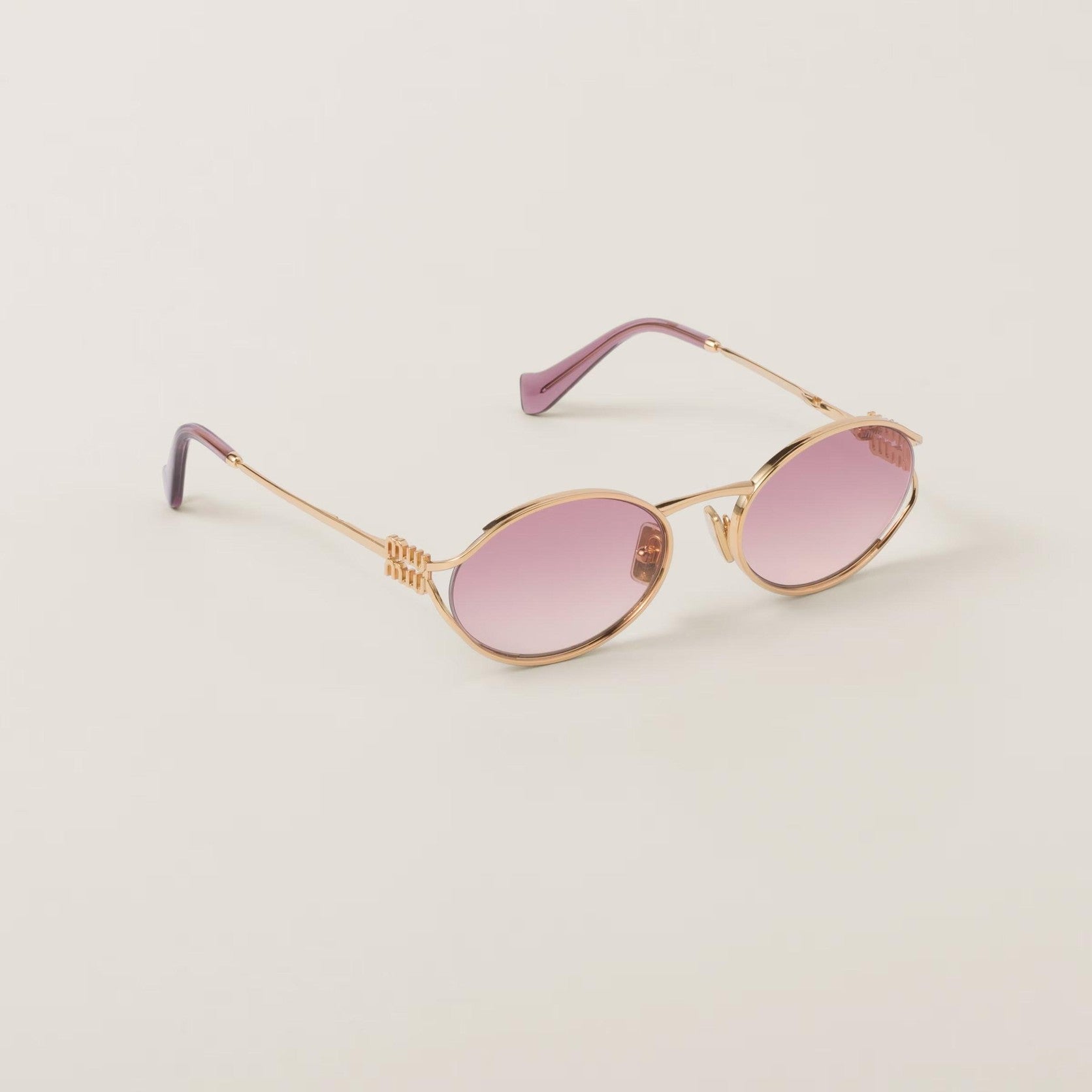 Image of Miu Miu oval metal glasses in rose gold with adjustable nose pads, UV protection.