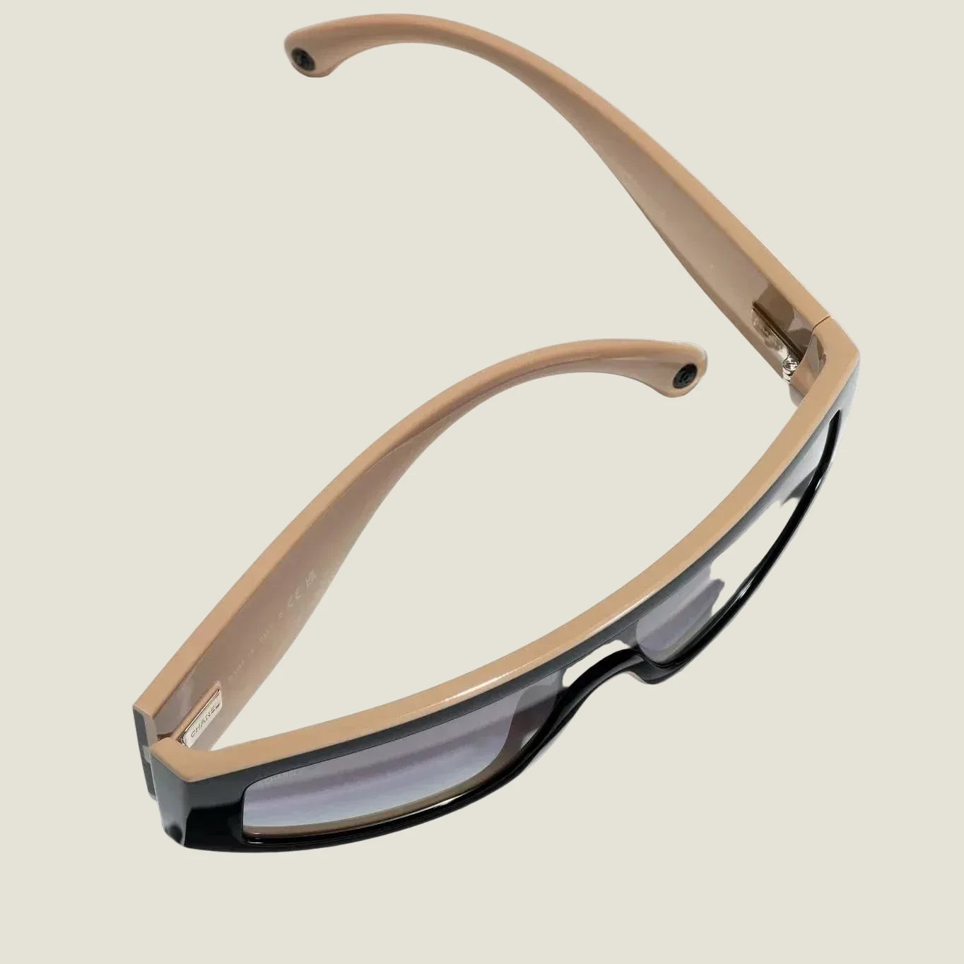 Black and brown CHANEL sunglasses with plastic frame and adjustable nose pads, offering 100% UVA/UVB protection.
