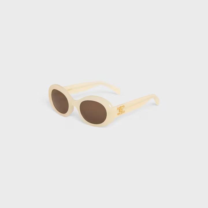 Image of Celine sunglasses with cream oval frames and dark lenses featuring logo detail.