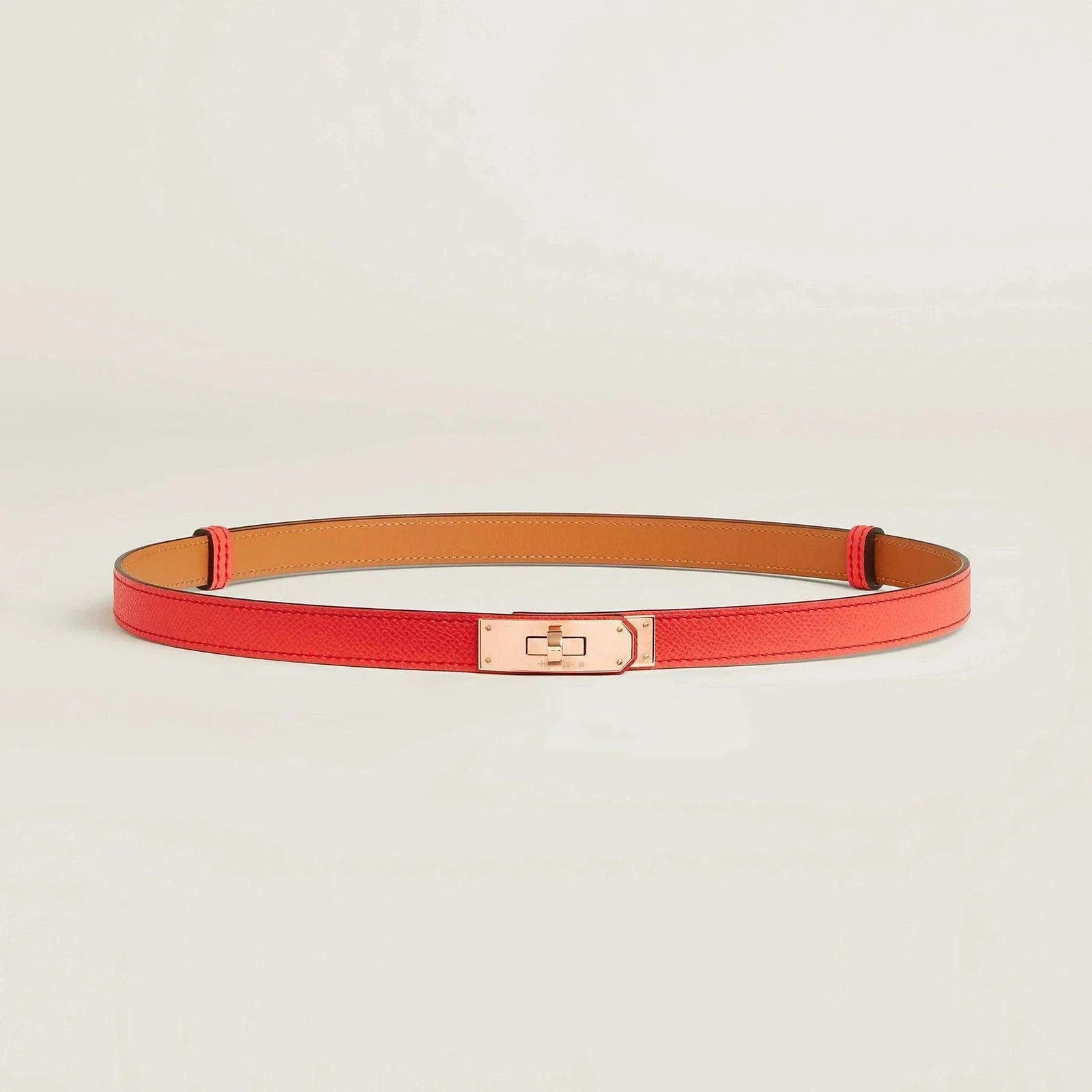 Hermès Kelly belt in red premium leather with sleek metallic buckle, luxurious minimalist design.
