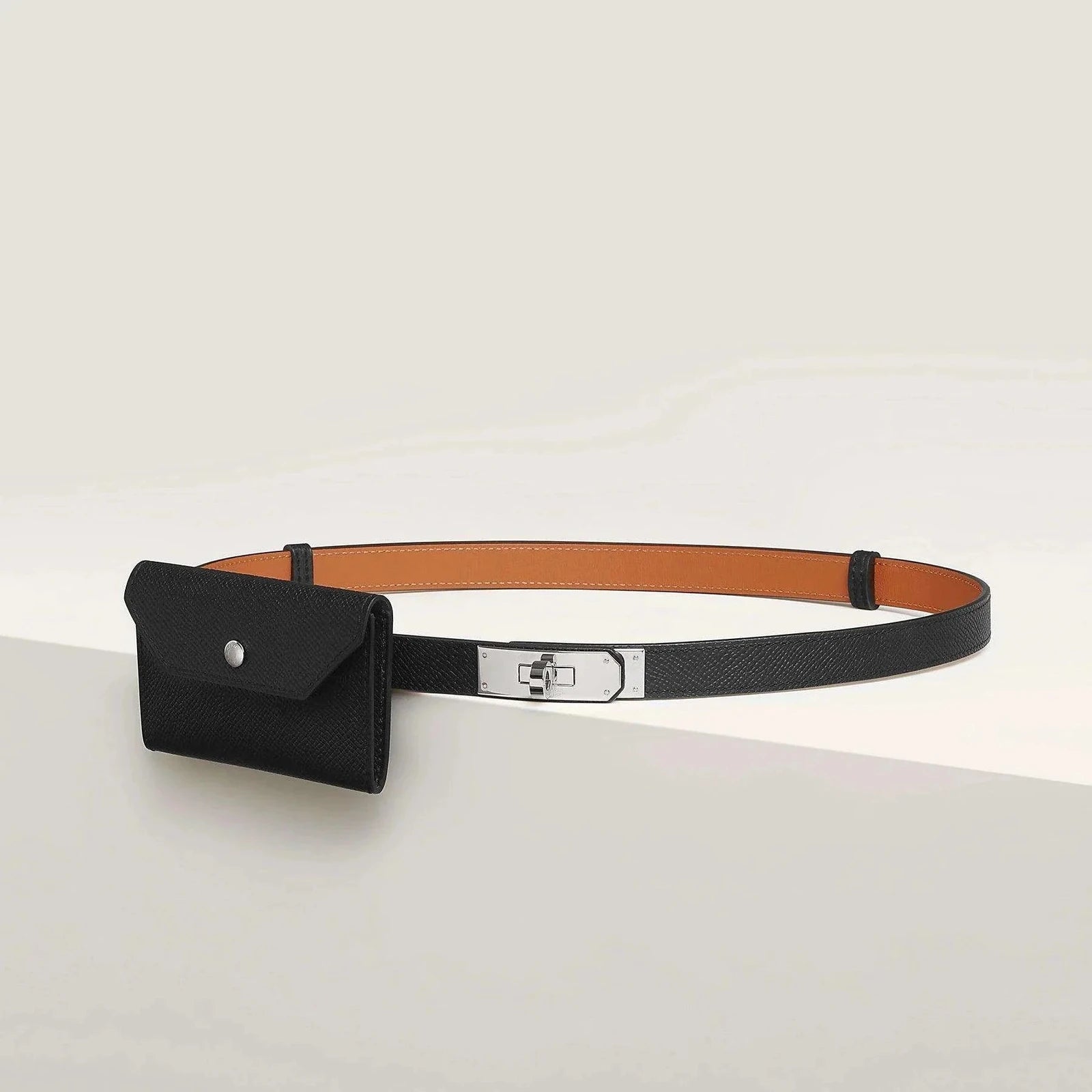 Image of Luxury Hermès leather belt with sleek metallic finish and attached pouch, showcasing minimalist elegance for both men and women.