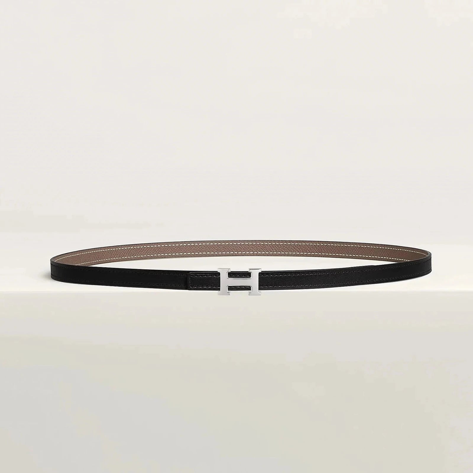 Image of Hermes belt with metallic buckle on display, showcasing luxury craftsmanship and minimalist design.