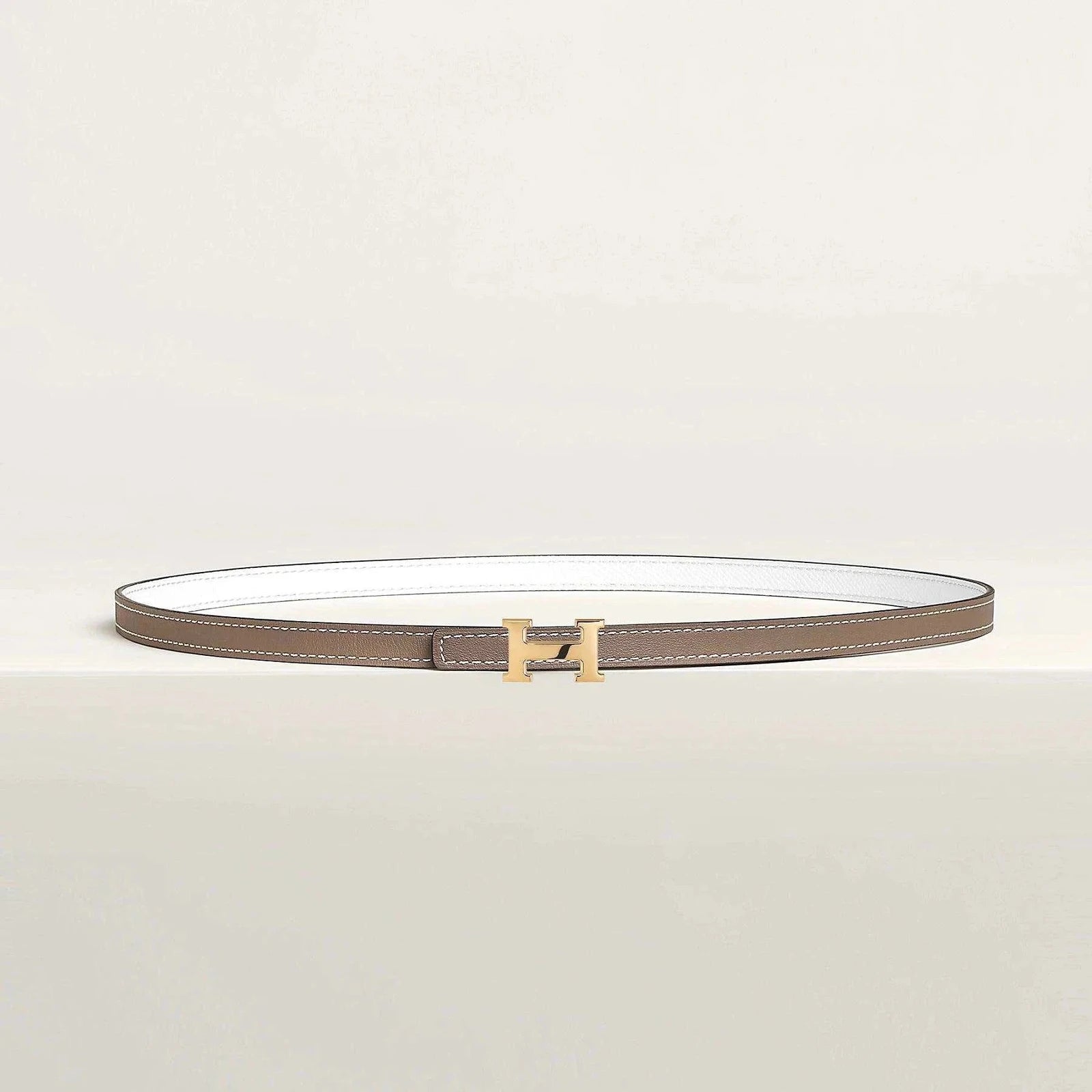 Image of Hermes leather belt with gold H buckle, luxury reversible design.