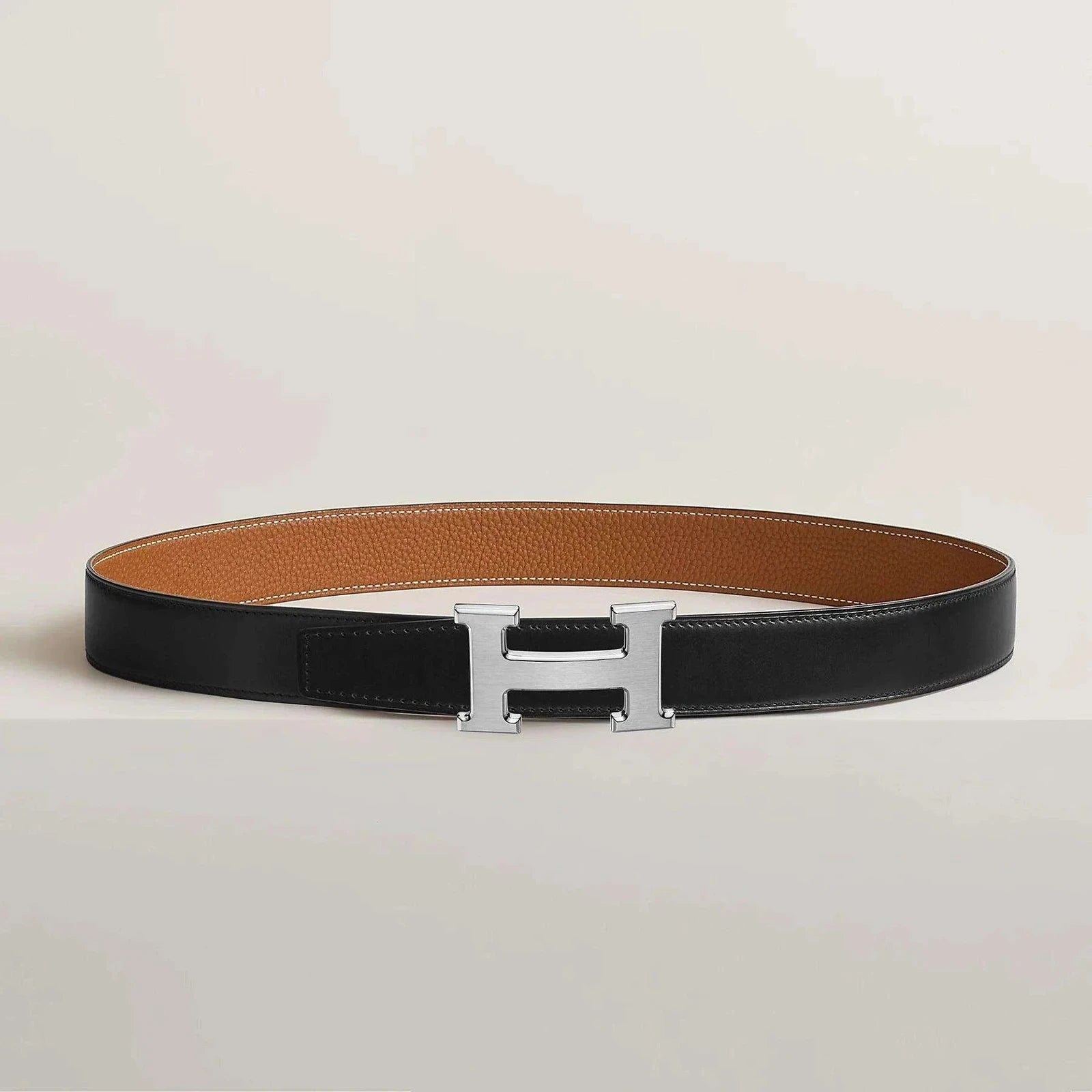 Hermes belt with metallic H buckle, reversible leather design, elegant and minimalist.