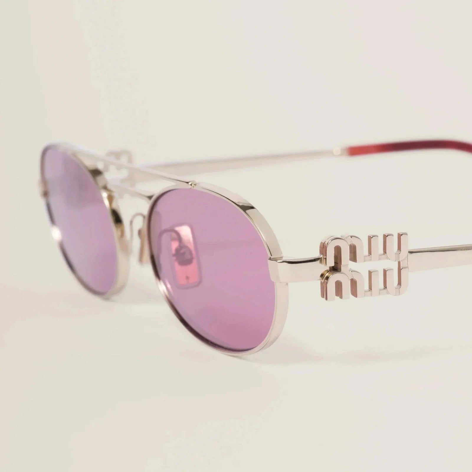 Image of Miu Miu thin metal frame sunglasses with black plastic detailing, adjustable nose pads, and UVA/UVB protection.