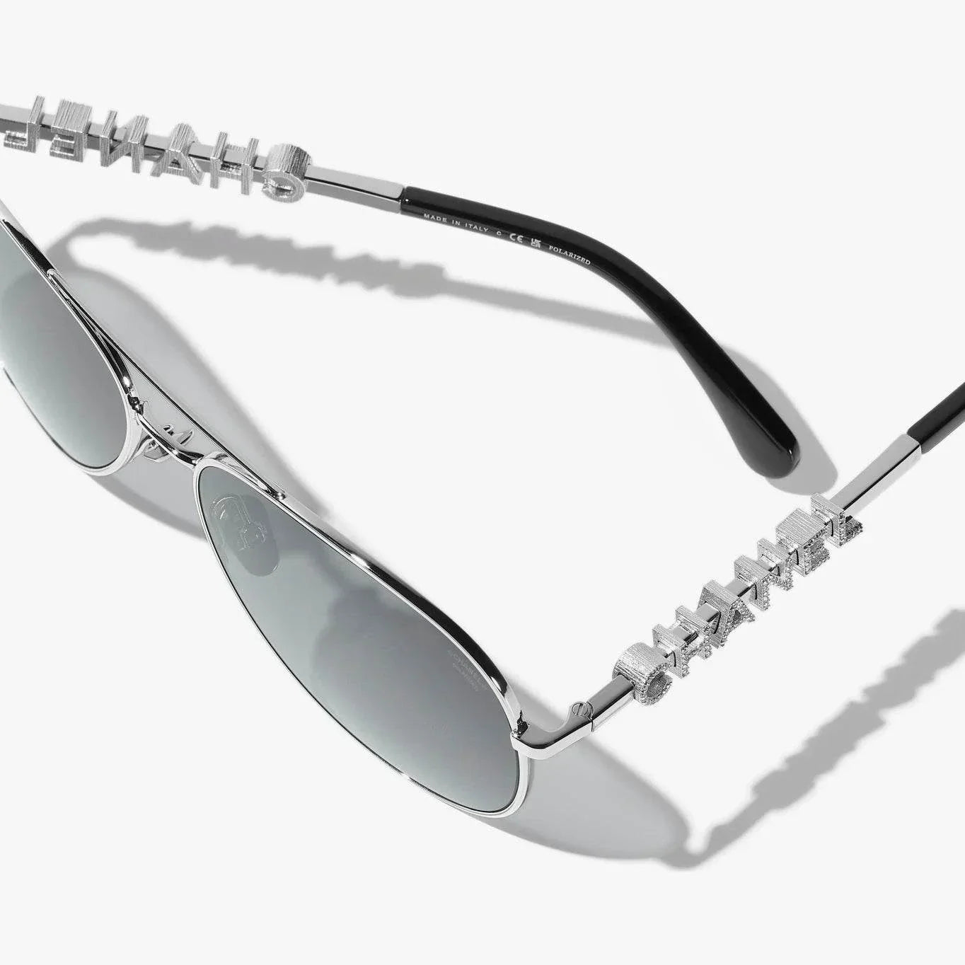 Silver CHANEL sunglasses with plastic frame, UVA/UVB protection, adjustable nose pads.