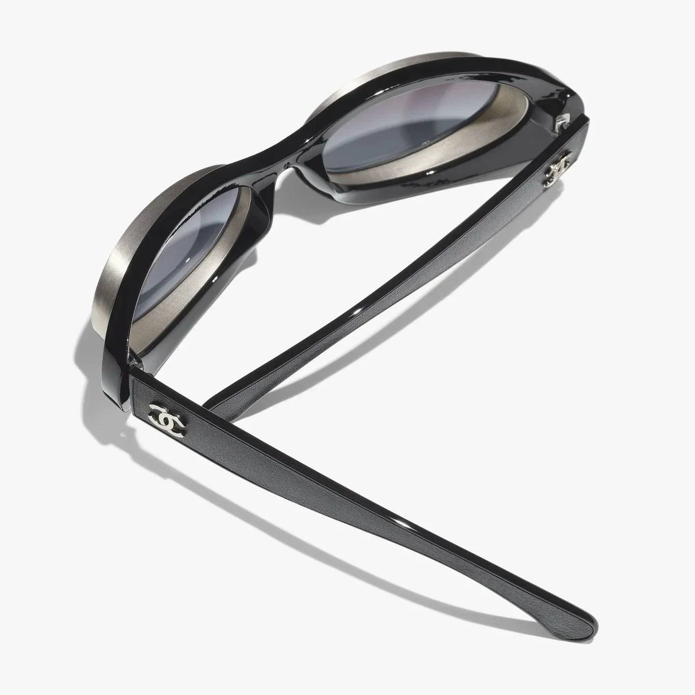 Image of CHANEL sunglasses, black and silver, plastic and metal frame, UVA/UVB protection, adjustable nose pads.