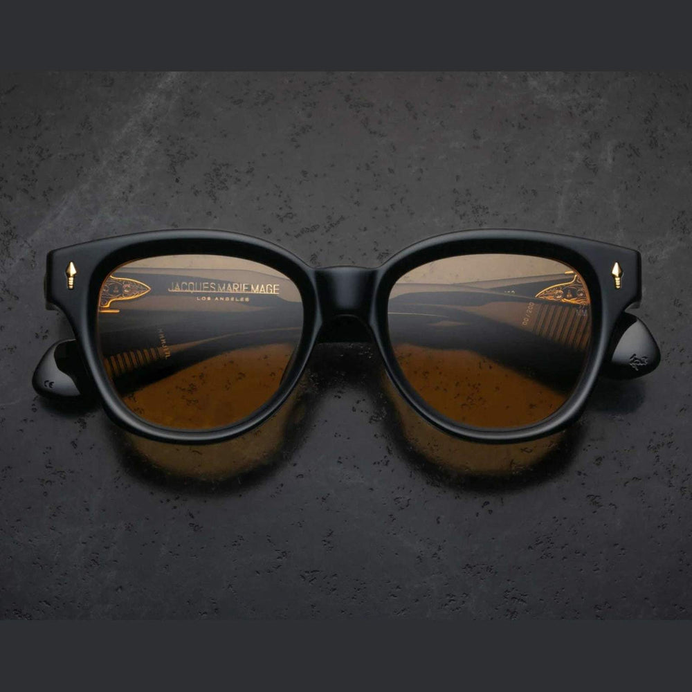 משקפי שמש Jacques Marie Mage MOJAVE שחורות עם מסגרת פלסטיק איכותית, הגנה מלאה מפני UVA/UVB ורפידות אף מתכווננות.
